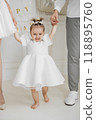 Happy toddler celebrating birthday with family in white attire 118895760