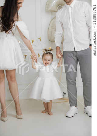 Happy family celebrating toddler's birthday in white outfits 118895761