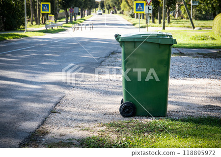 Green garbage container on the side of the street. Urban environment and waste processing industry 118895972
