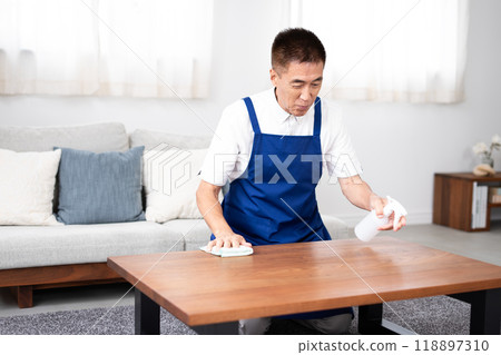 Senior male housekeeper in a white polo shirt with a blue apron Senior male housekeeper in a white polo shirt with a blue apron 118897310