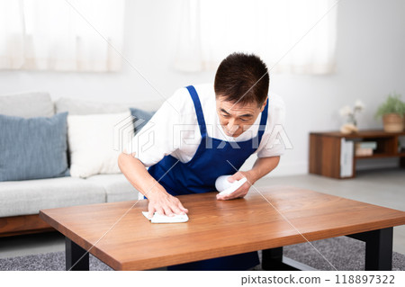 Senior male housekeeper in a white polo shirt with a blue apron 118897322