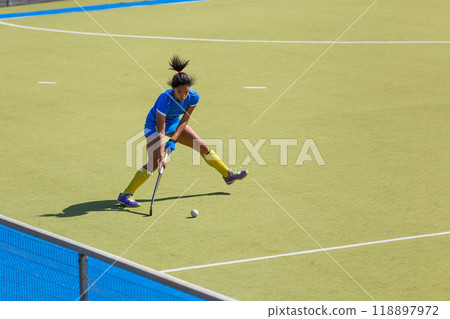 Young female field hockey player passing the ball through the pitch Young female field hockey player passing the ball through the pitch 118897972