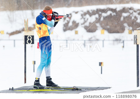Athlete shooting in standing position at the range in a biathlon competition 118898076