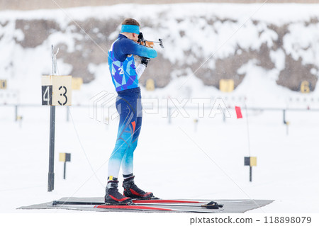 Athlete shooting in standing position at the range in a biathlon competition 118898079