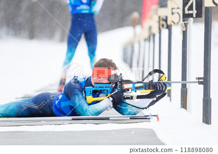 Athlete shooting in prone position at the range in a biathlon competition Athlete shooting in prone position at the range in a biathlon competition 118898080