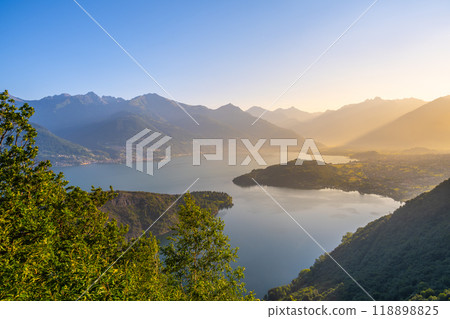 A beautiful mountain range with a lake in the foreground. The lake is calm and the mountains are covered in trees. The sky is clear and the sun is shining brightly. The scene is peaceful and serene A beautiful mountain range with a lake in the foreground. The lake is calm and the mountains are covered in trees. The sky is clear and the sun is shining brightly. The scene is peaceful and serene 118898825