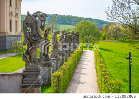 Baroque statues elegantly decorate the pathway at the Kuks hospital complex in Czechia, surrounded by lush greenery and hills under a clear sky. Baroque statues elegantly decorate the pathway at the Kuks hospital complex in Czechia, surrounded by lush greenery and hills under a clear sky. 118898869