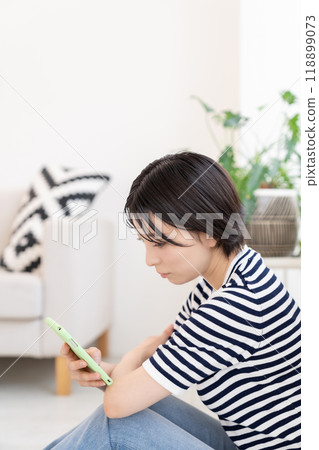 Woman looking at smartphone in the room Woman looking at smartphone in the room 118899073