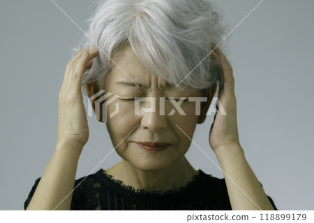 A gray-haired senior woman holding her head A gray-haired senior woman holding her head 118899179