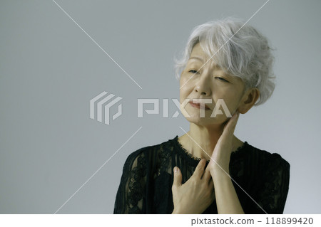 A gray-haired senior woman with her hands on her throat A gray-haired senior woman with her hands on her throat 118899420