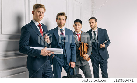 Businessmen hold important work materials, posing in formal attire and expressing readiness for business decisions against white background. 118899471
