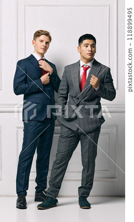Team. Male Professionals showcasing modern elegance, both present strong and poised stances against white studio background. Team. Male Professionals showcasing modern elegance, both present strong and poised stances against white studio background. 118899495