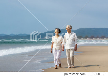 成熟的夫婦手牽手沿著海灘散步 成熟的夫婦手牽手沿著海灘散步 118900130