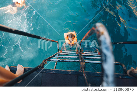 Experience the invigorating thrill of a refreshing summer swim from the boat ladders edge 118900870