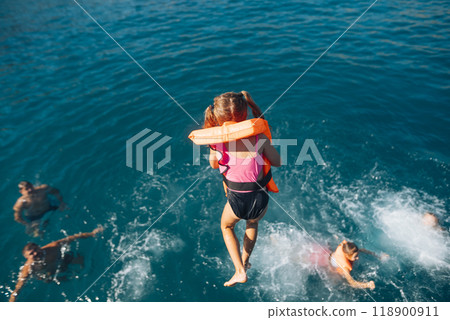 Joyful Summer Fun Kids Joyfully Playing in the Ocean with Brightly Colored Life Vests Joyful Summer Fun Kids Joyfully Playing in the Ocean with Brightly Colored Life Vests 118900911