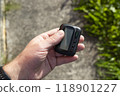 Pager with display in hand of man on street. Portable wireless device for receiving text messages 118901227