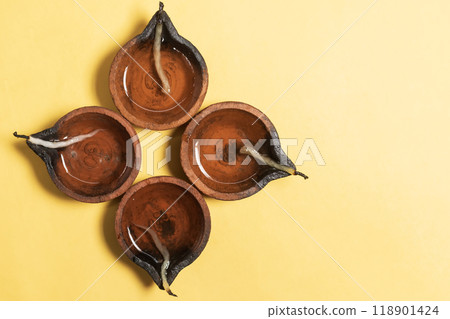 Happy Diwali - Traditional clay lamps arranged on yellow background during Diwali festival celebrations. Copy space for text. 118901424