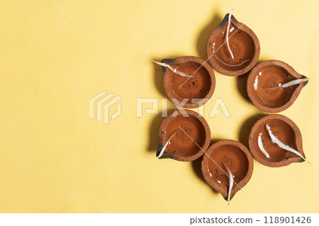 Happy Diwali - Hindu traditional clay diya arrangement for Diwali festival of lights celebration on yellow background. Happy Diwali - Hindu traditional clay diya arrangement for Diwali festival of lights celebration on yellow background. 118901426