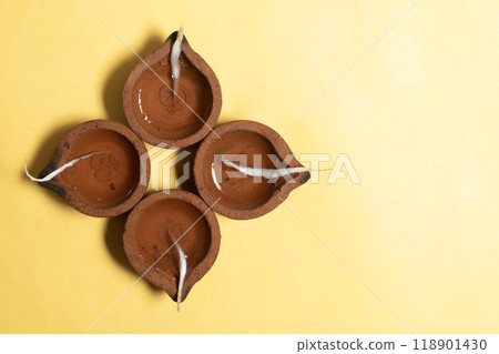 Happy Diwali - Traditional clay lamps arranged on yellow background during Diwali festival celebrations. 118901430