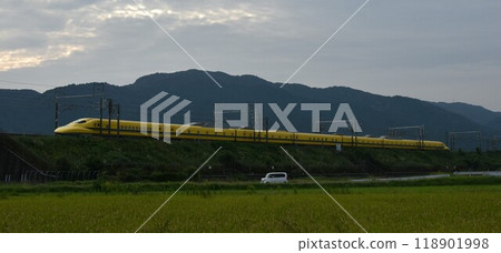 A yellow Shinkansen train racing through the Showa era countryside 118901998