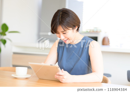 A woman using a touch pen to operate a tablet device 118904384
