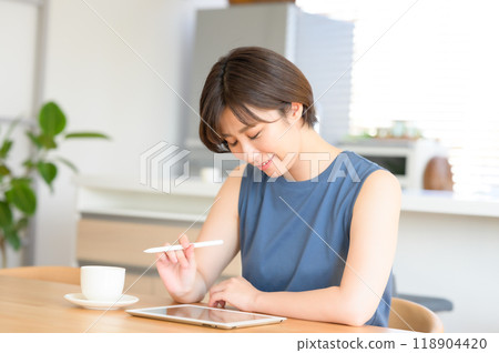 A woman using a touch pen to operate a tablet device A woman using a touch pen to operate a tablet device 118904420