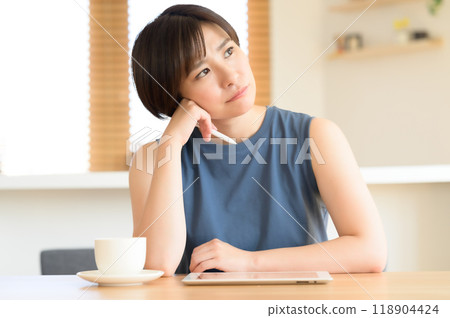 A woman using a touch pen to operate a tablet device 118904424