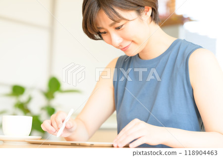 A woman using a touch pen to operate a tablet device 118904463