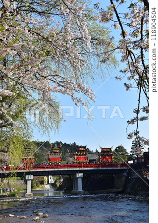 Takayama City, Gifu Prefecture, Japan, Spring Takayama Festival, Cherry blossoms in full bloom and food stalls crossing Nakabashi Bridge, beautiful fresh greenery, blue sky and Miyagawa River 118904504