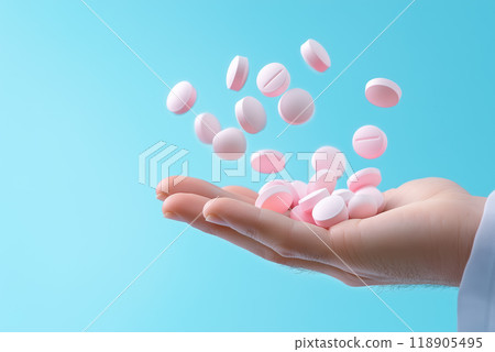 Hand holding pink pills against a soft blue background 118905495