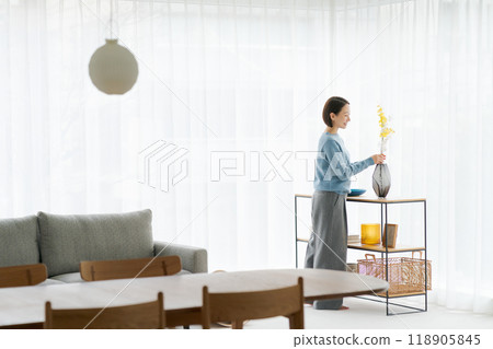 A woman in her 30s decorating her room with flowers A woman in her 30s decorating her room with flowers 118905845