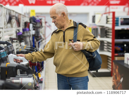 Senor man pensioner buying Upright Vacuum Cleaner in showroom of electrical appliance store Senor man pensioner buying Upright Vacuum Cleaner in showroom of electrical appliance store 118906717