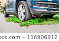 Environmental balance depicted through ivy overtaking car tire, nature reclaiming urban mechanical spaces, symbolizing green resilience and contrast. 118906912