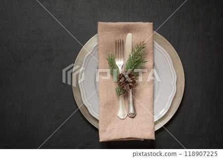 Christmas table place setting with silverware and dark evergreen decor. Top view. Holiday background. 118907225