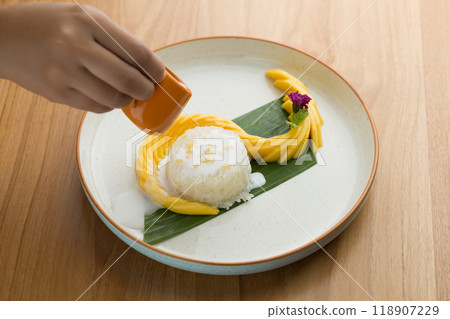 Mango sticky rice, featuring coconut milk as a key ingredient and topped with roasted mung bean. 118907229