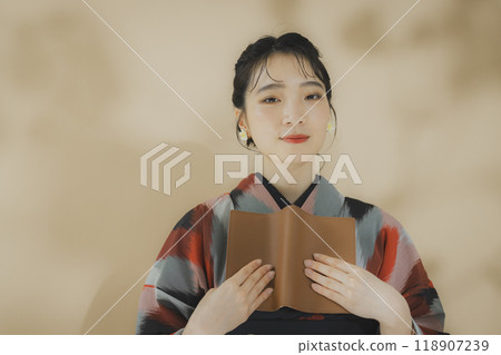 A woman in a kimono reading 118907239