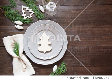 Christmas table setting with white decor, silverware and decorations on wooden board. Top view. Rustic style. Christmas table setting with white decor, silverware and decorations on wooden board. Top view. Rustic style. 118907247