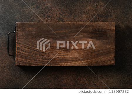 Wooden cutting board with metal handle on dark brown kitchen table top. Space for design. Top view. flat lay. Cooking concept. Wooden cutting board with metal handle on dark brown kitchen table top. Space for design. Top view. flat lay. Cooking concept. 118907282