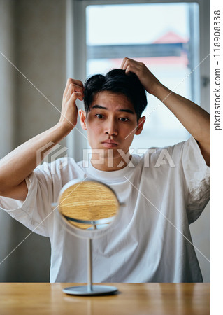 A young man in his 20s styling his hair 118908338