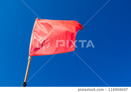 Warning red flag is waving on strong wind above blue sky 118908697