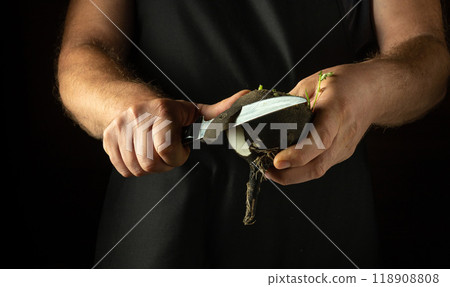 A chef peels a black radish with a knife. Preparing to cook a dietary vegetable dish in a hotel kitchen. Advertising space 118908808
