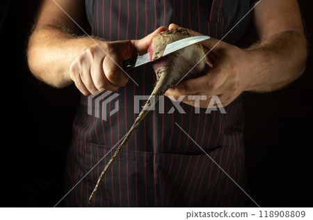 A chef peels raw beets with a knife. Preparing to cook a dietary vegetable dish in a restaurant kitchen. Advertising space A chef peels raw beets with a knife. Preparing to cook a dietary vegetable dish in a restaurant kitchen. Advertising space 118908809