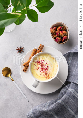 Golden milk latte with turmeric and rose petals. Trendy Indian drink Moon milk with natural spices. 118910113
