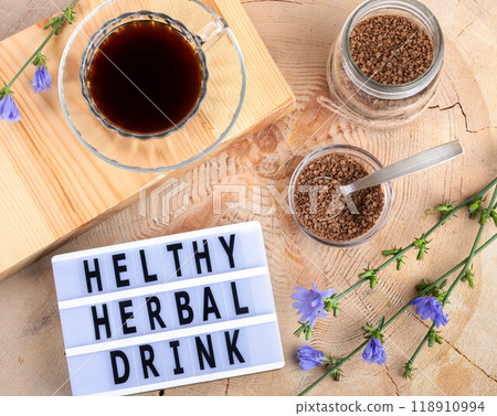 Chicory tea cup, granular chicory, bloom twigs, inscription by black letters. Wooden table. Top view 118910994