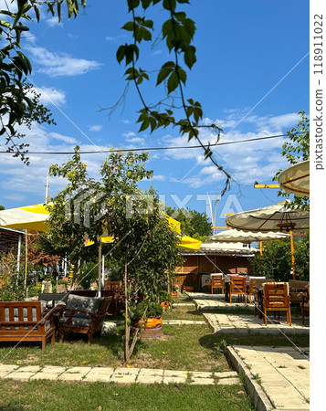 Outdoor seating area with large canvas umbrellas and wooden furniture under a clear blue sky in hotel resort creates an inviting and relaxed atmosphere. Setting is perfect for enjoying sunny days in a Outdoor seating area with large canvas umbrellas and wooden furniture under a clear blue sky in hotel resort creates an inviting and relaxed atmosphere. Setting is perfect for enjoying sunny days in a 118911022
