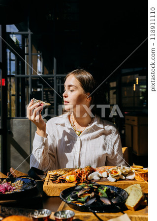 Woman enjoying seafood platter with oysters and shrimp in restaurant. Food lifestyle content 118911110