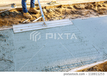 Leveling concrete using trowel during pouring of freshly concreted sidewalks Leveling concrete using trowel during pouring of freshly concreted sidewalks 118911253