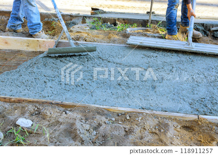 Worker using trowel leveling concrete during freshly cement pouring of sidewalk 118911257