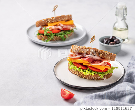 Two toast club sandwiches made of grain bread with cheddar cheese and bacon stuffed with tomatoes Two toast club sandwiches made of grain bread with cheddar cheese and bacon stuffed with tomatoes 118911637