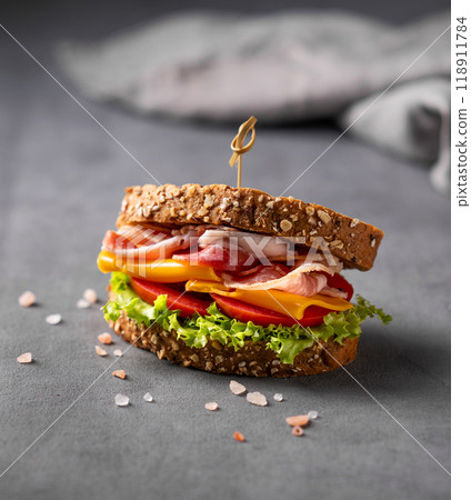 Club sandwich on a board with a bacon, cheese, tomato and lettuce on a dark background 118911784
